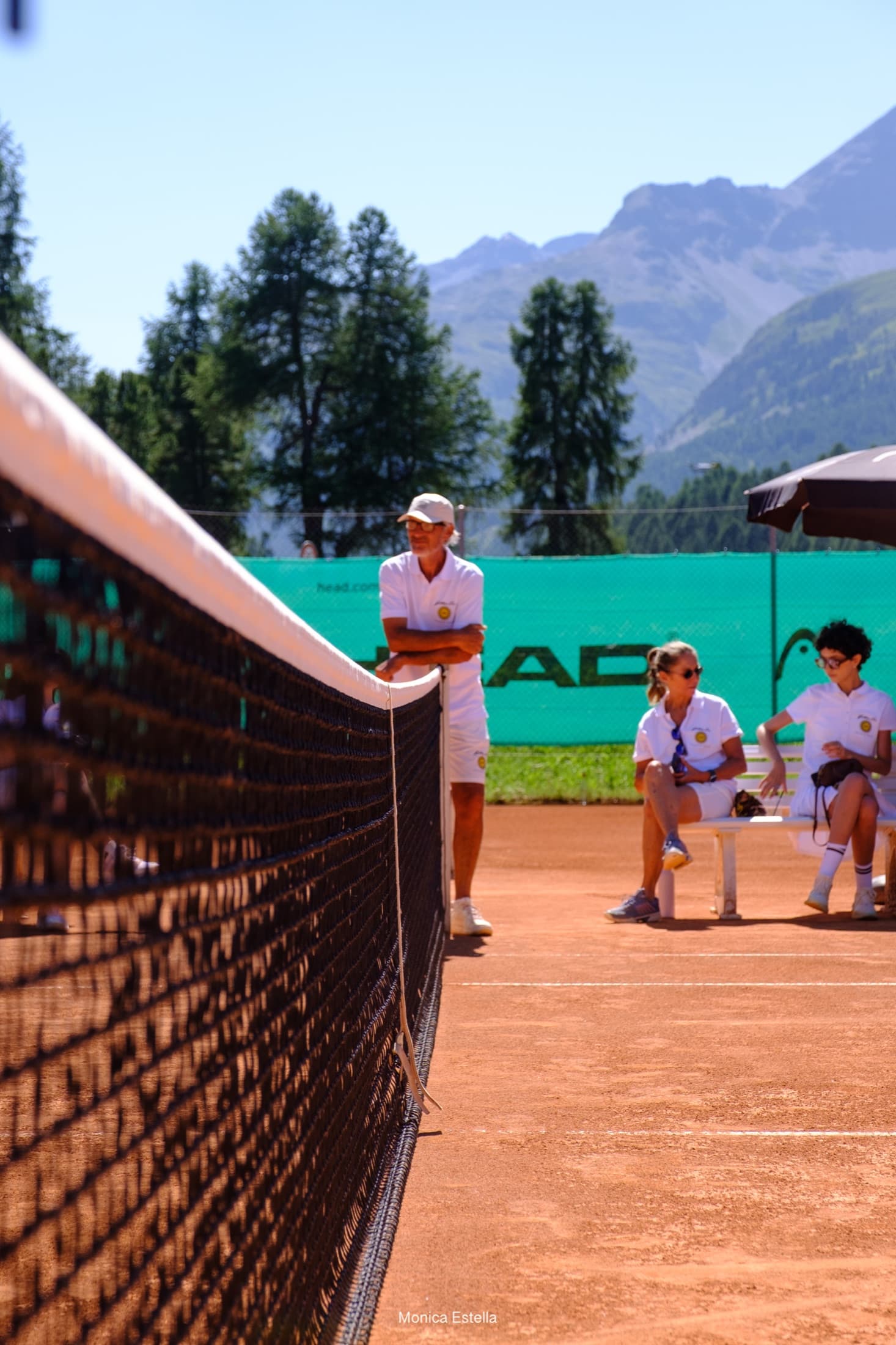 Golden Era players meeting beside a clay tennis court in the mountains