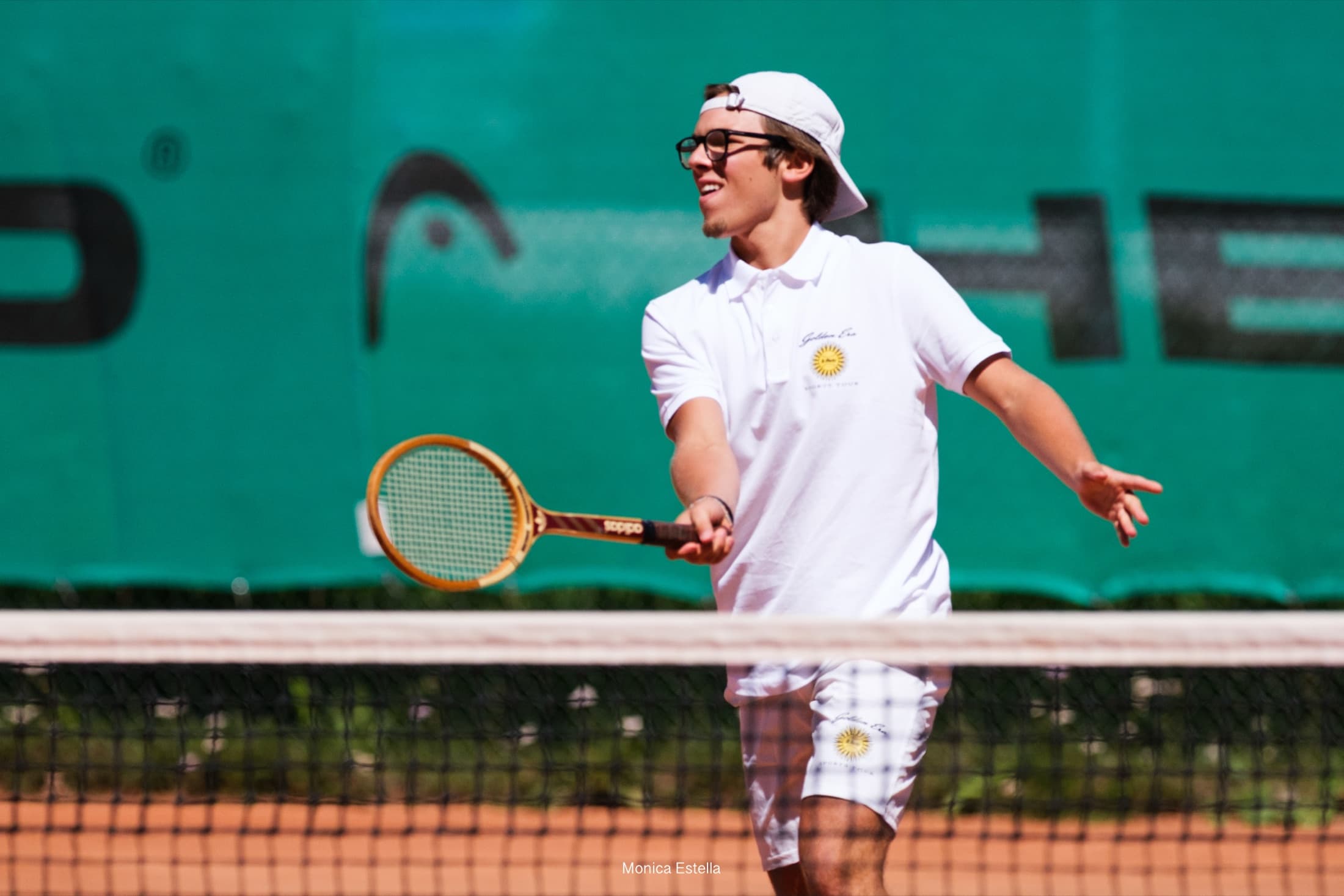 Golden Era participant playing with a wooden tennis racquet on clay